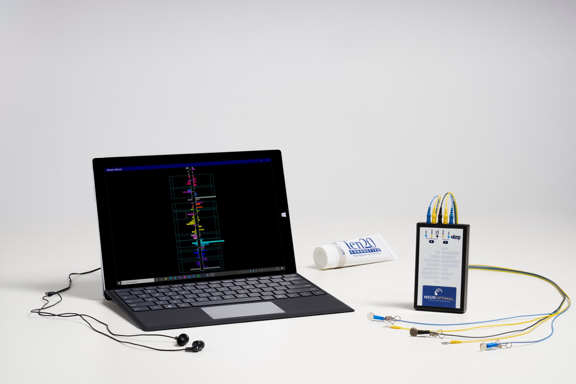 NeurOptimal neurofeedback system featuring a laptop, zAmp device, colored electrodes, and conductive paste.